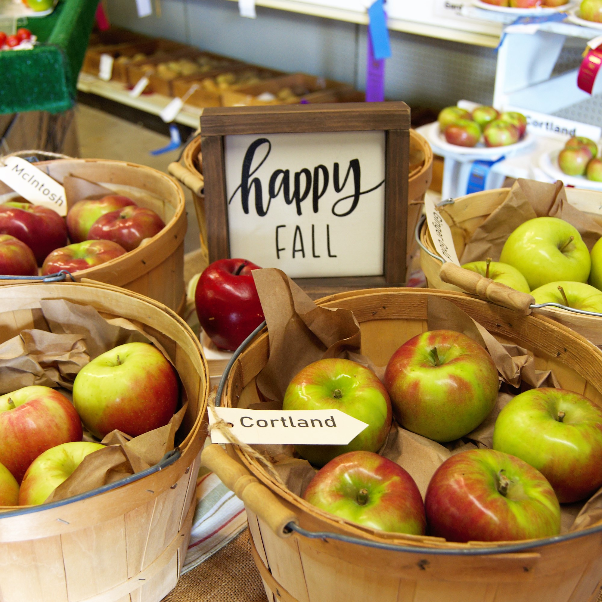 Baskets of apples and a sign that says happy fall