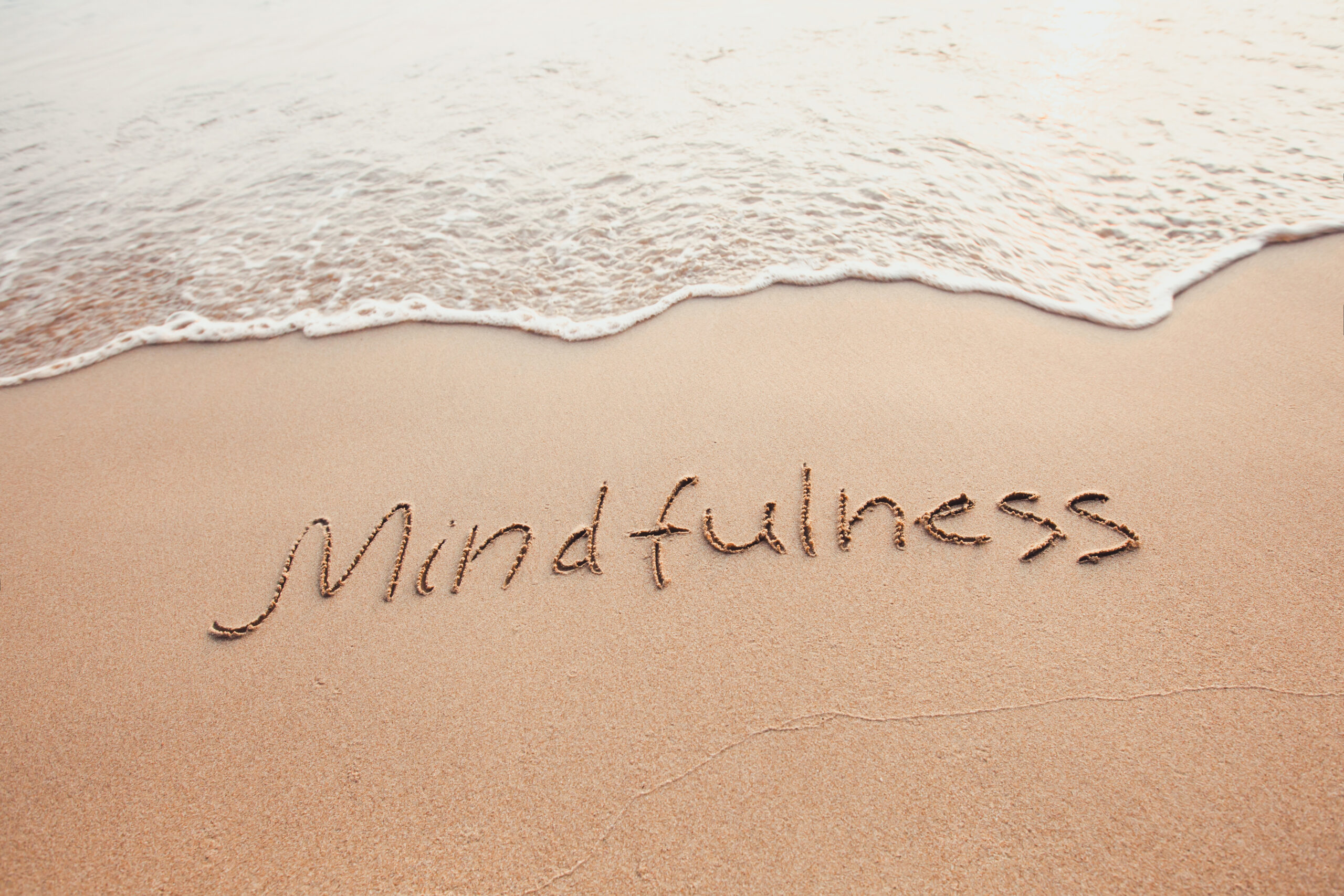 mindfulness concept, mindful living, text written on the sand of beach