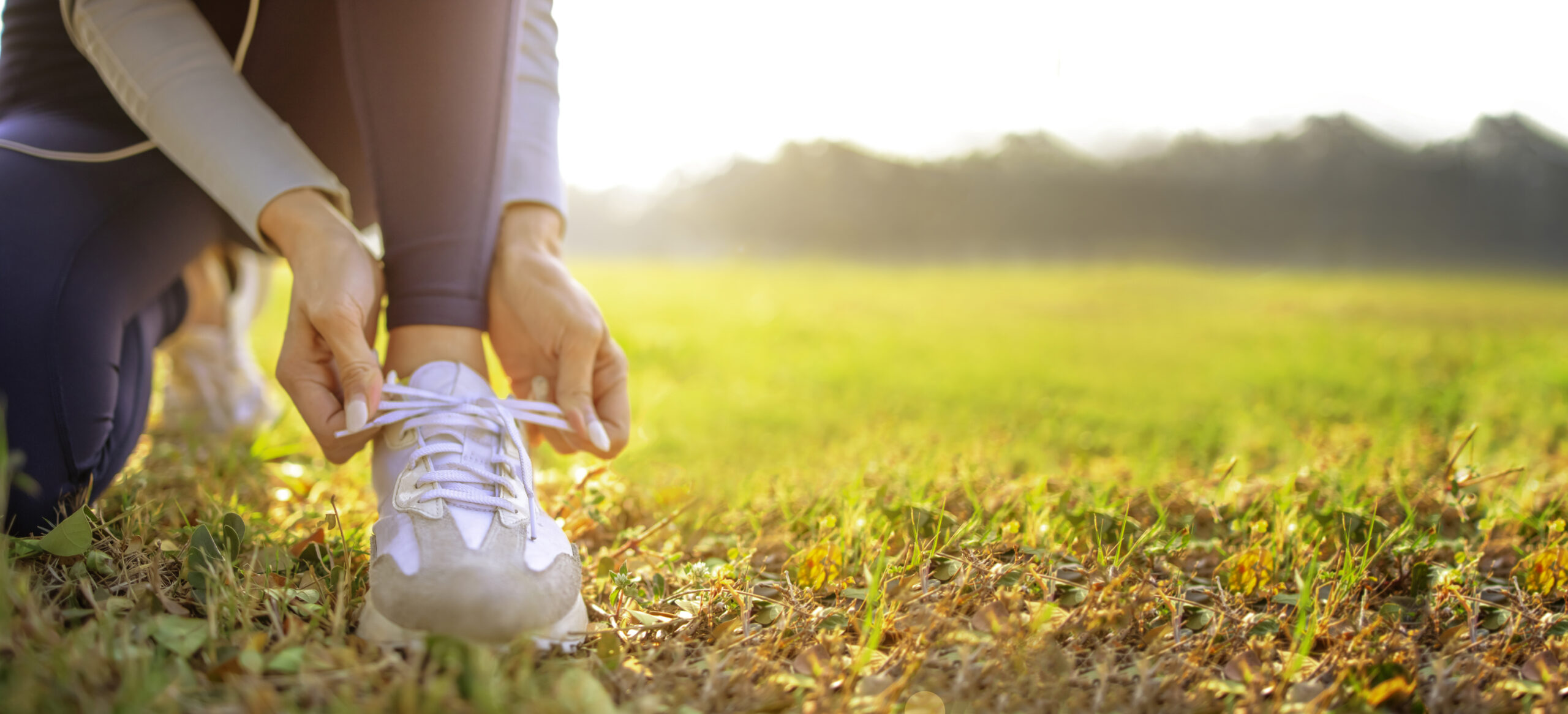 young woman runner tying her shoes preparing for a jog outside at morning