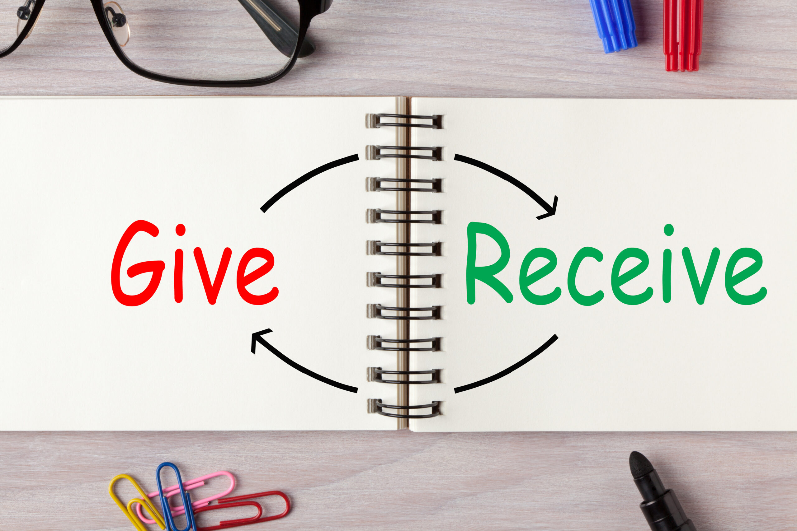 Give and Receive written on open spiral notebook and various stationery. Concept words