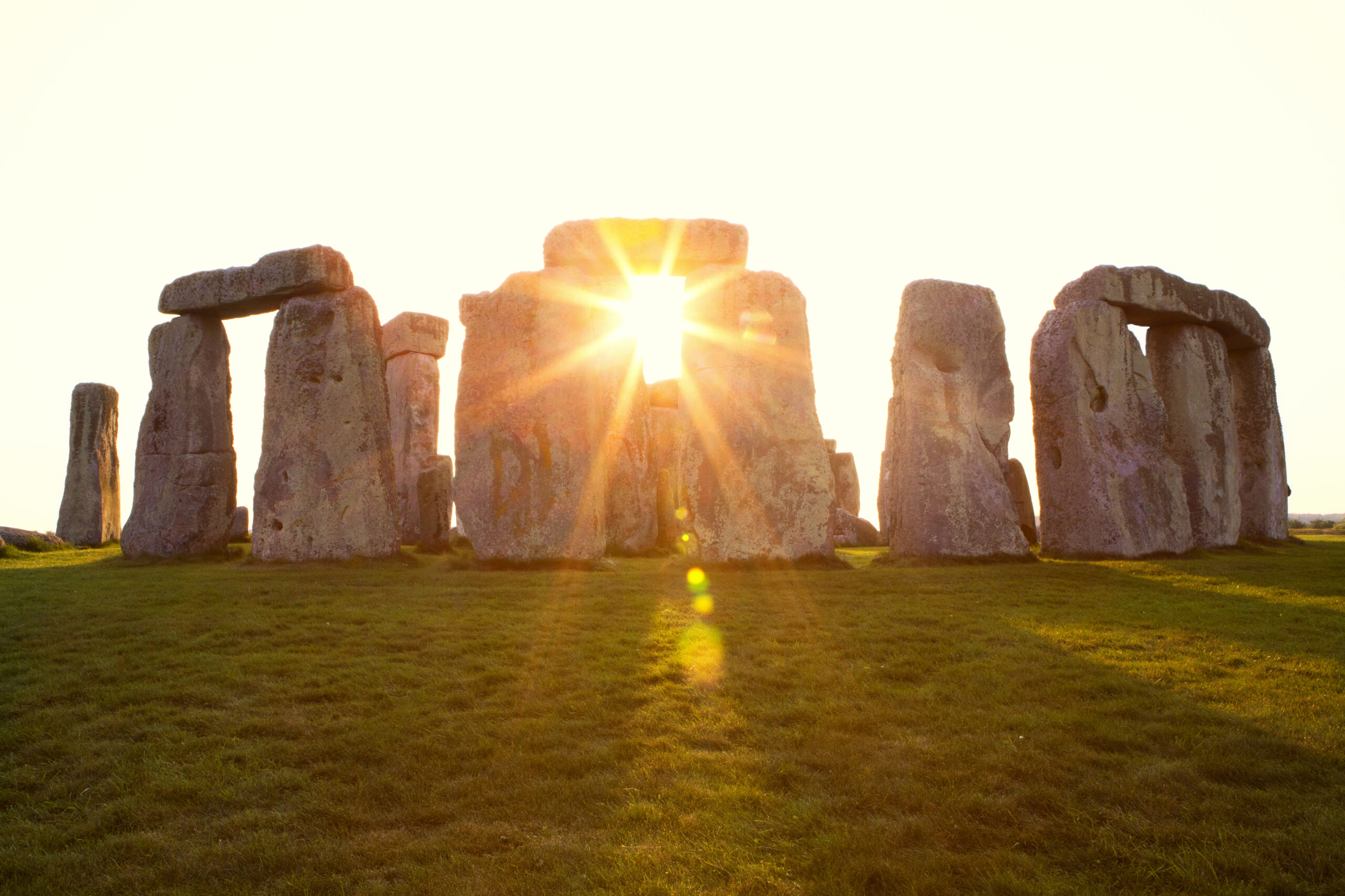 Close-up view of ancient stones during sunset at UNESCO World Heritage Site at Stonehenge, Wiltshire, UK. Sun shines through the stones. Major tourist destination, archeological and pilgrimage site during Summer Solstice and Winter Solstice. Visible grain, softer focus.