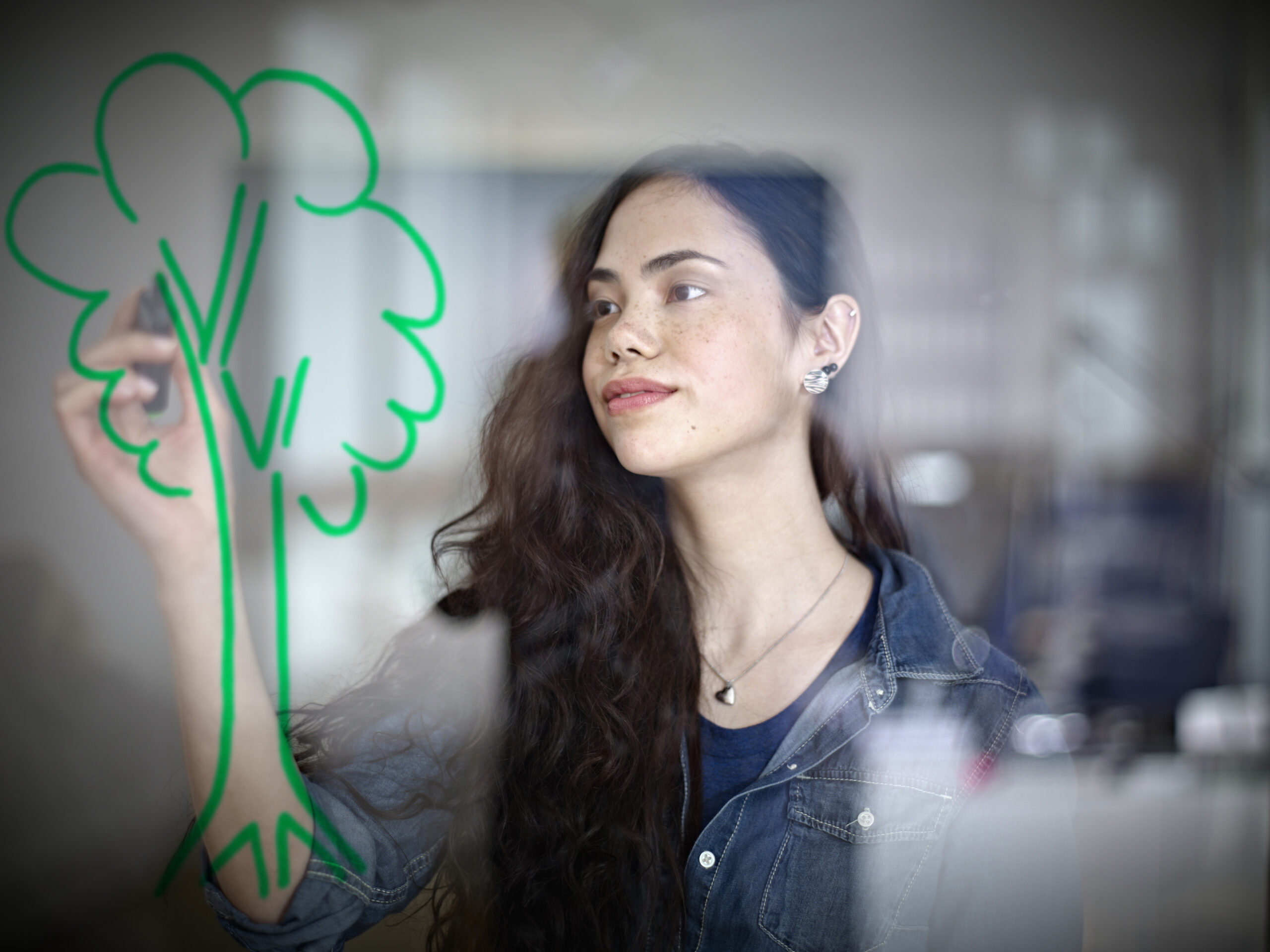 Germany, Cologne, Young woman drawing tree on glass