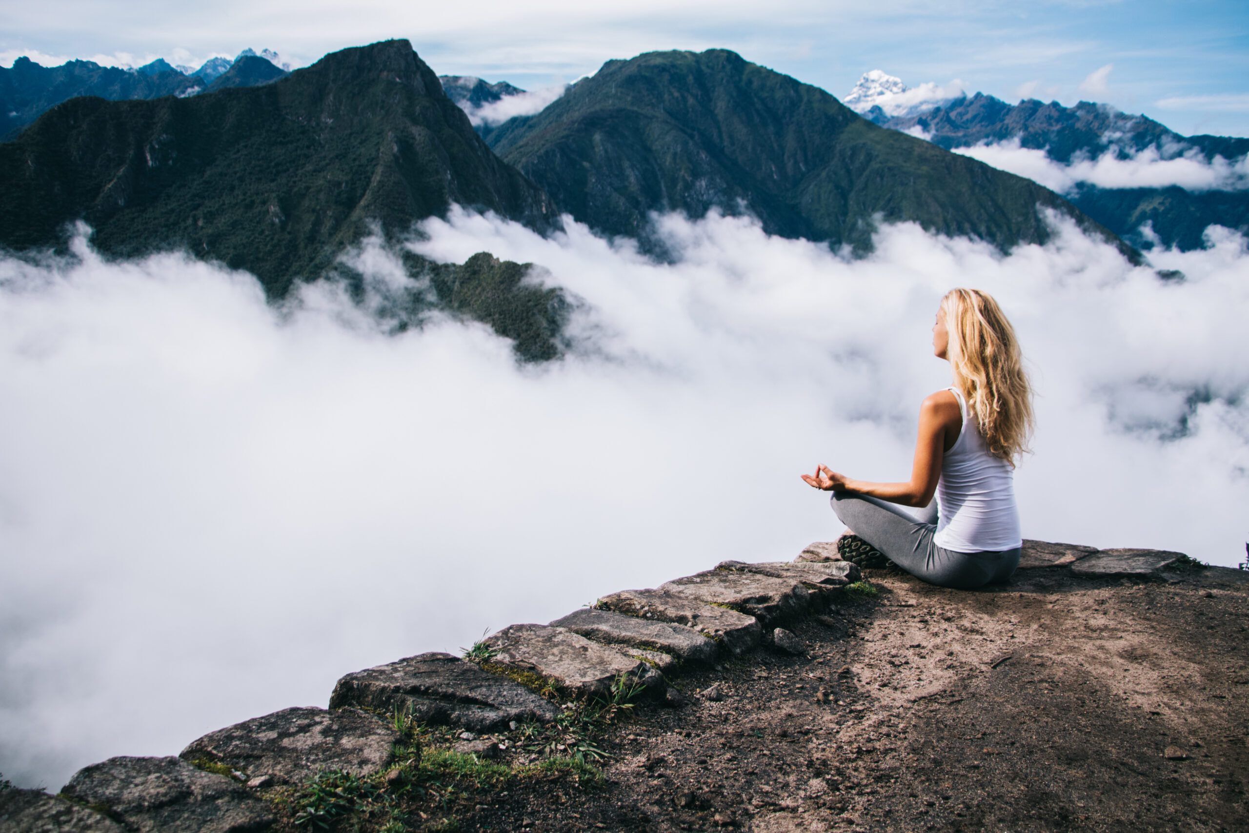 Calm and inspiration on peak with Machu Picchu, relaxed woman tourist sitting in lotus pose and admiring scenery of natural environment feeling harmony during yoga meditation in tranquil place